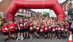 Hundreds of young runners line up under a red inflatable start line 